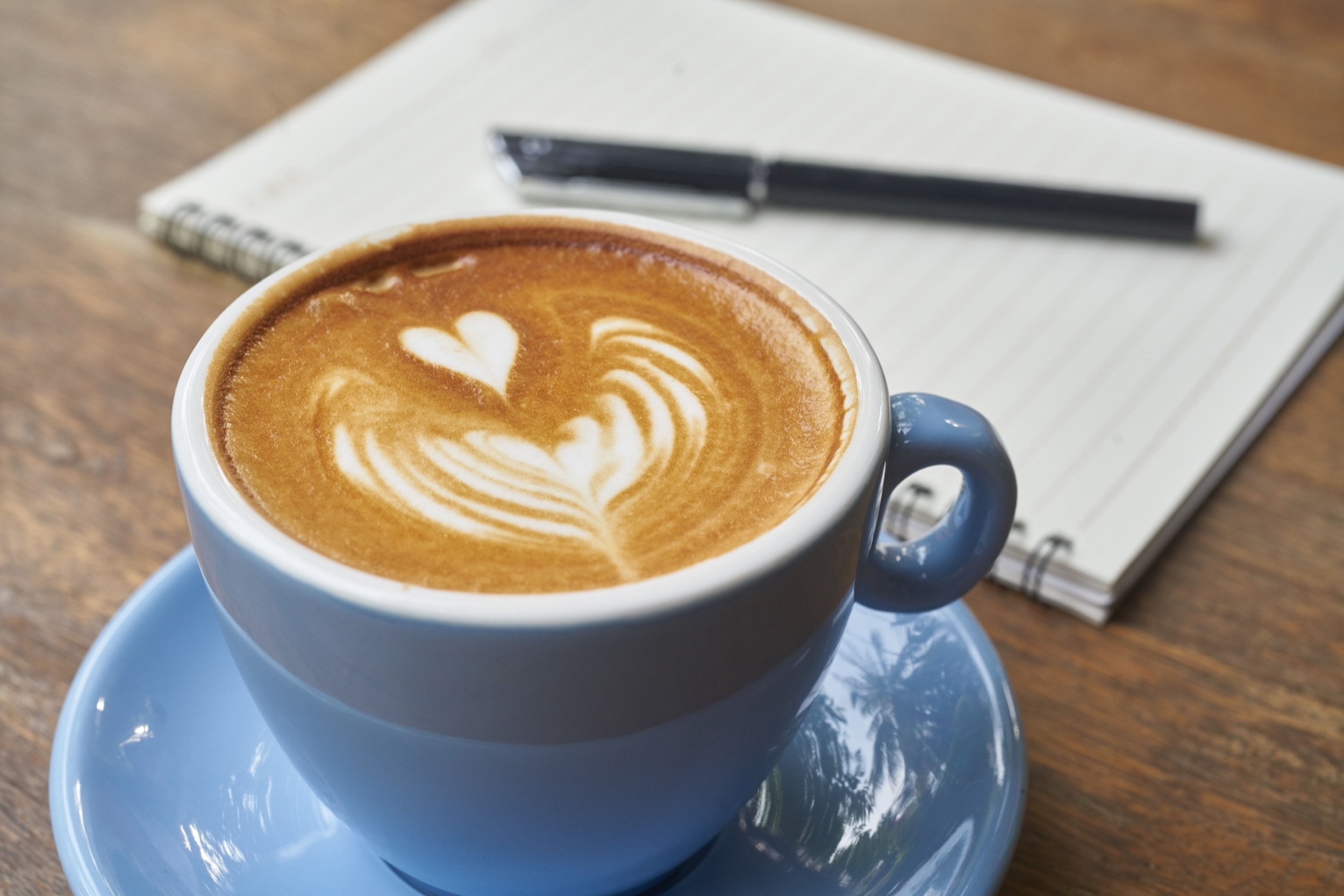 An open notebook and coffee on a linen surface in morning light